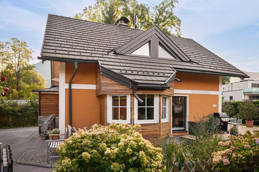 Rückansicht des Hauses mit Holzverkleidung, Erkerfenster und gepflegtem Vorgarten.