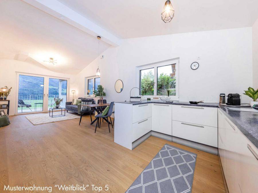 Heller offener Wohn- und Kochbereich mit moderner Einbauküche und Zugang zur Terrasse.
