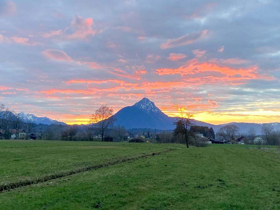 Weite Felder und majestätische Berge im warmen Licht des Sonnenuntergangs.