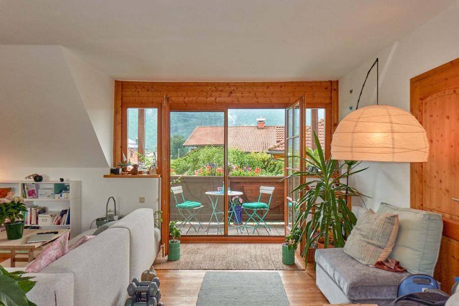 Gemütlicher Wohnbereich mit Holzboden, Balkonzugang und Blick auf die grüne Umgebung.