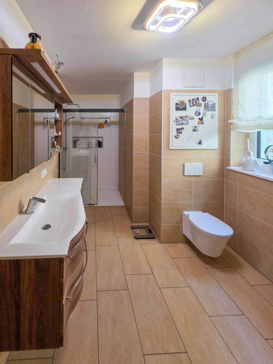 Modernes Badezimmer mit großer Dusche, Doppelwaschbecken und Holzunterschrank.