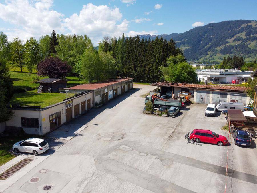 Blick von oben auf den großen Parkplatz und die angrenzenden Gebäude inmitten einer grünen Umgebung.