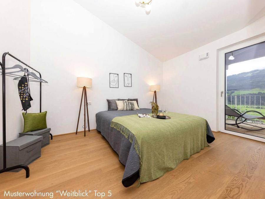 Helles Schlafzimmer mit Holzboden, Doppelbett und direktem Zugang zum Balkon mit Bergblick.