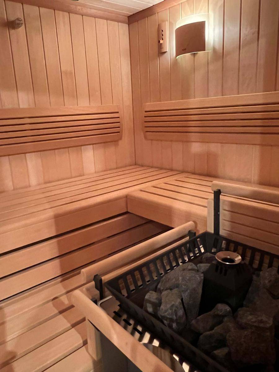 Traditionelle Holzsauna mit Bänken und Saunaofen, bereit für entspannende Momente.