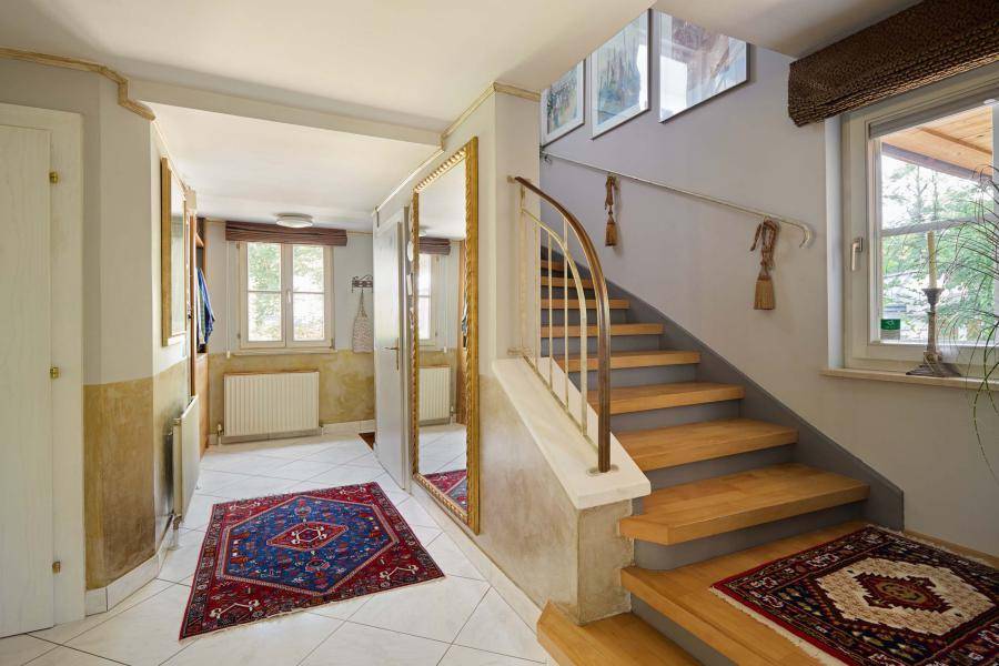 Heller Eingangsbereich mit Treppe, großem Spiegel und Fliesenboden, einladend gestaltet.