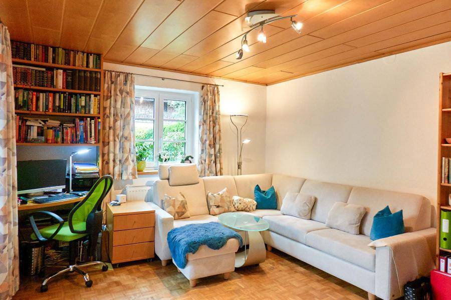 Wohnzimmer mit bequemer Sitzecke, Bücherregal und integriertem Arbeitsplatz.