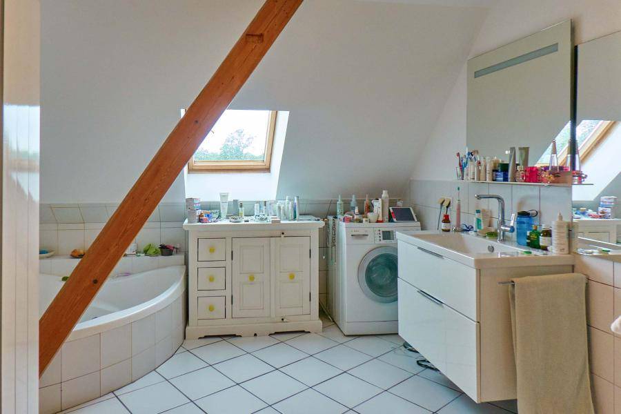 Helles Badezimmer mit Eckbadewanne, Dachfenster und Waschbeckenunterschrank.