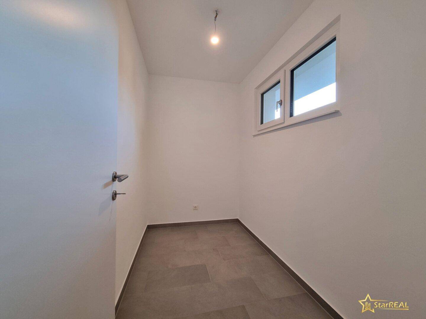 Kleiner, heller Raum mit Fenster und Fliesenboden, ideal als Abstellraum oder Büro.