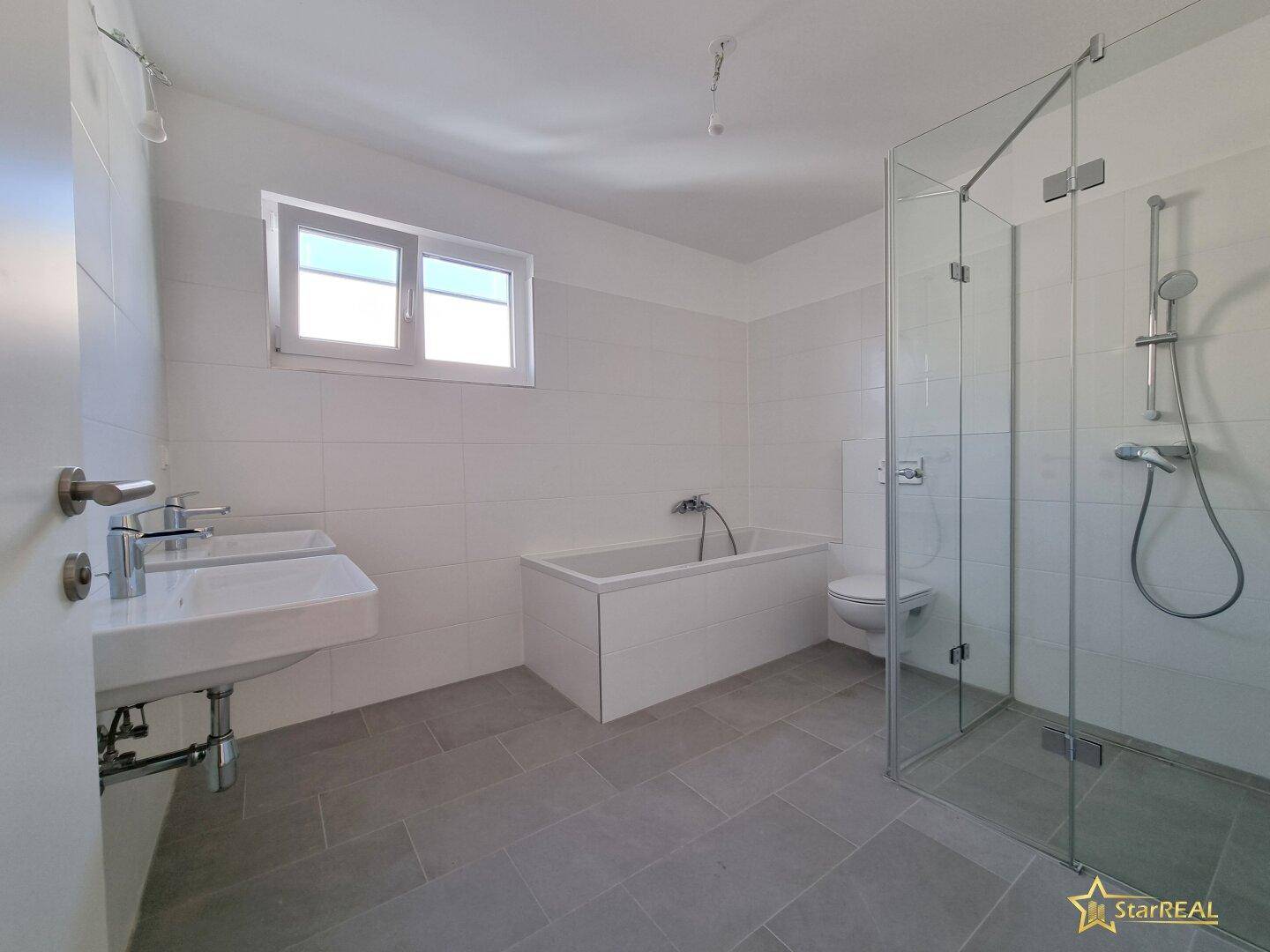Modernes Badezimmer mit Badewanne, begehbarer Dusche, Doppelwaschbecken und Fenster.