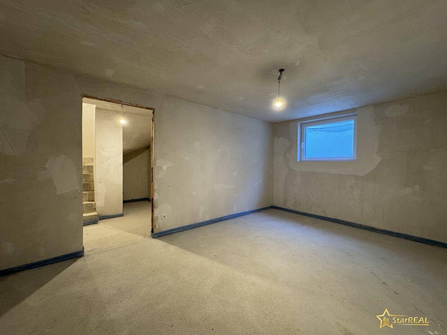 Geräumiger Rohbau mit Betonboden und einem Fenster, wartet auf den Innenausbau.