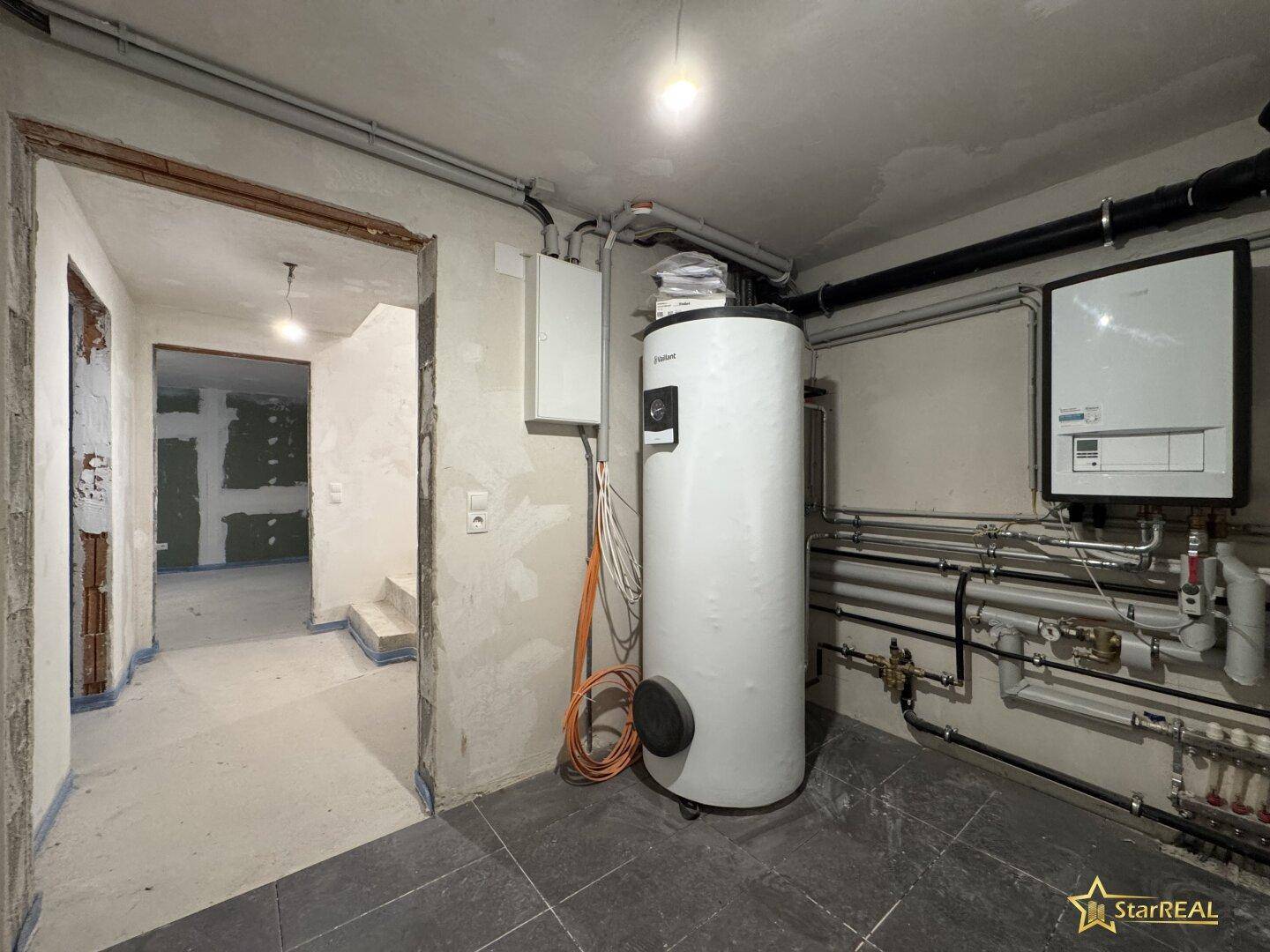 Technikraum mit Heizungsanlage und Warmwasserspeicher, bereit für den Betrieb.