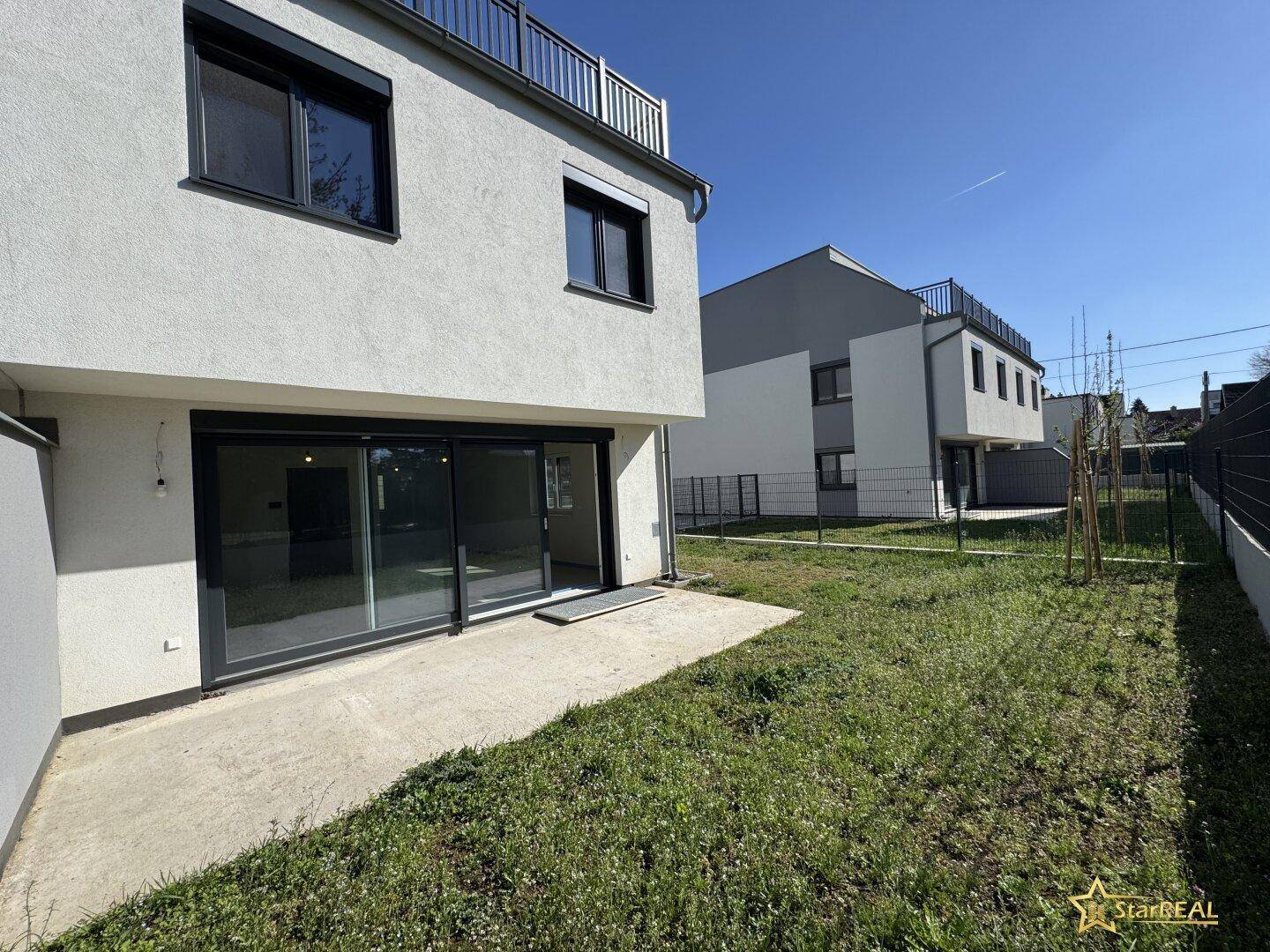 Neubau-Doppelhaushälfte mit kleiner Rasenfläche und Terrasse, bereit zur Gestaltung.