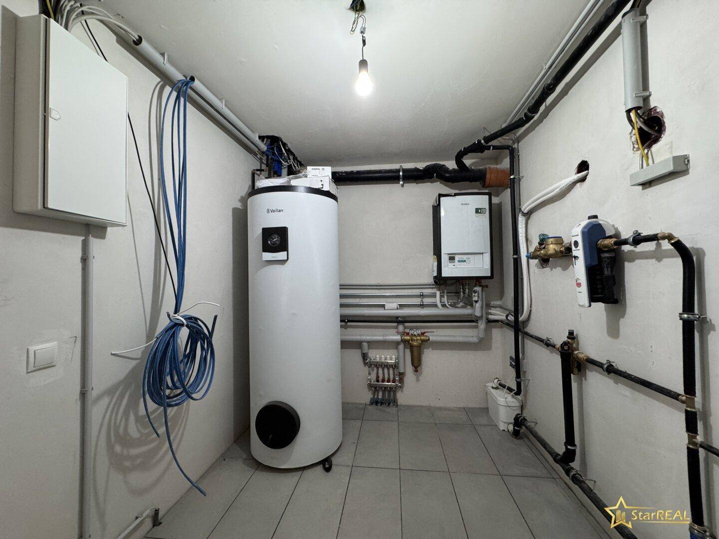 Technikraum mit Heizungsanlage, Warmwasserspeicher und elektrischen Installationen.
