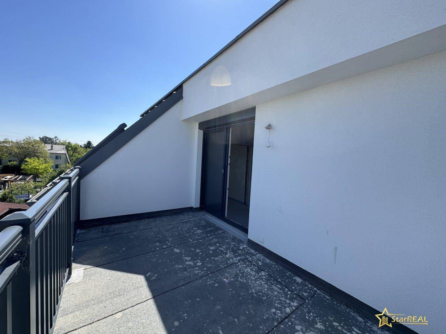 Sonnige Dachterrasse mit Schiebetür und Blick auf die umliegenden Häuser.