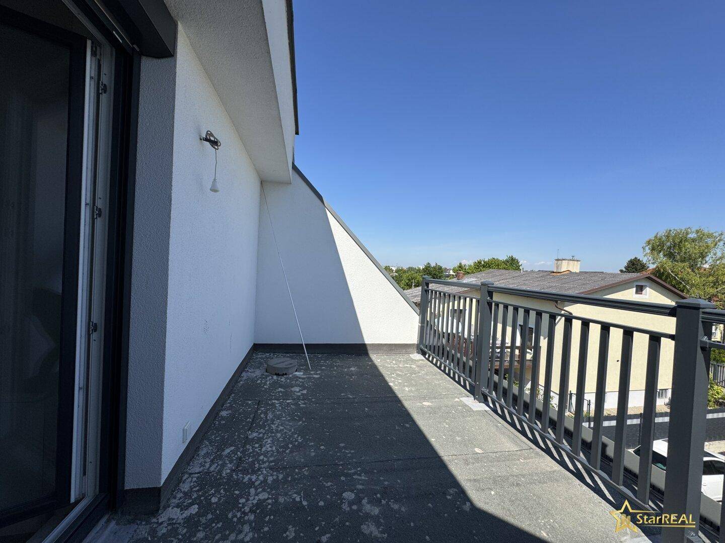 Unfertiger Balkon im Obergeschoss mit Metallgeländer und sonnigem Ausblick.