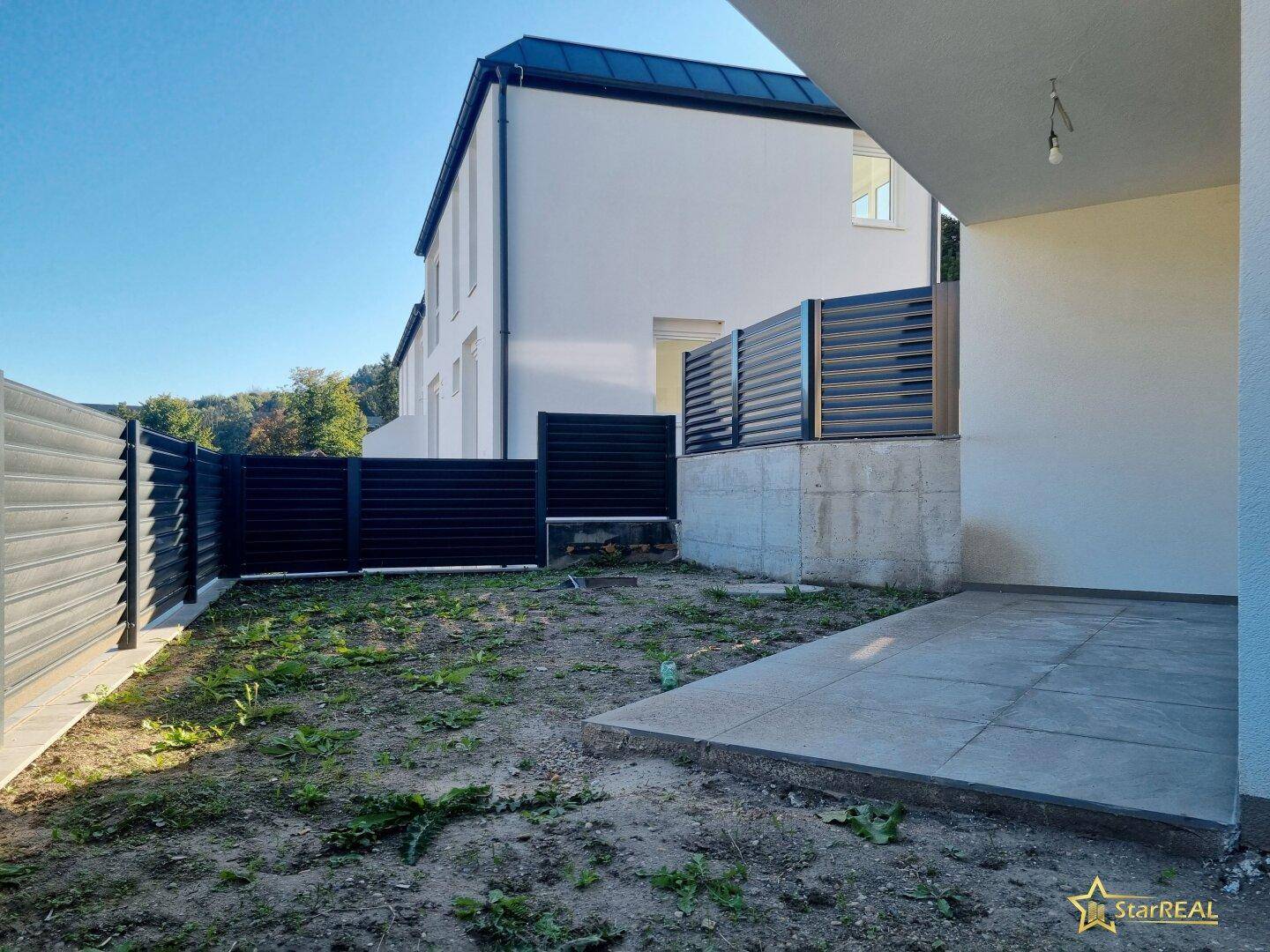 Gartenbereich mit Rasenfläche und Blick auf die moderne Gebäudefassade.