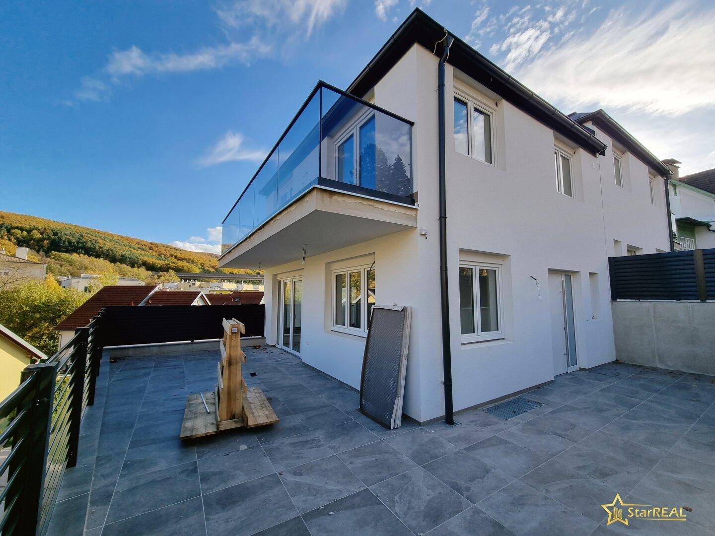 Geräumige Terrasse mit modernen Fliesen und Zugang zum Gartenbereich des Hauses.