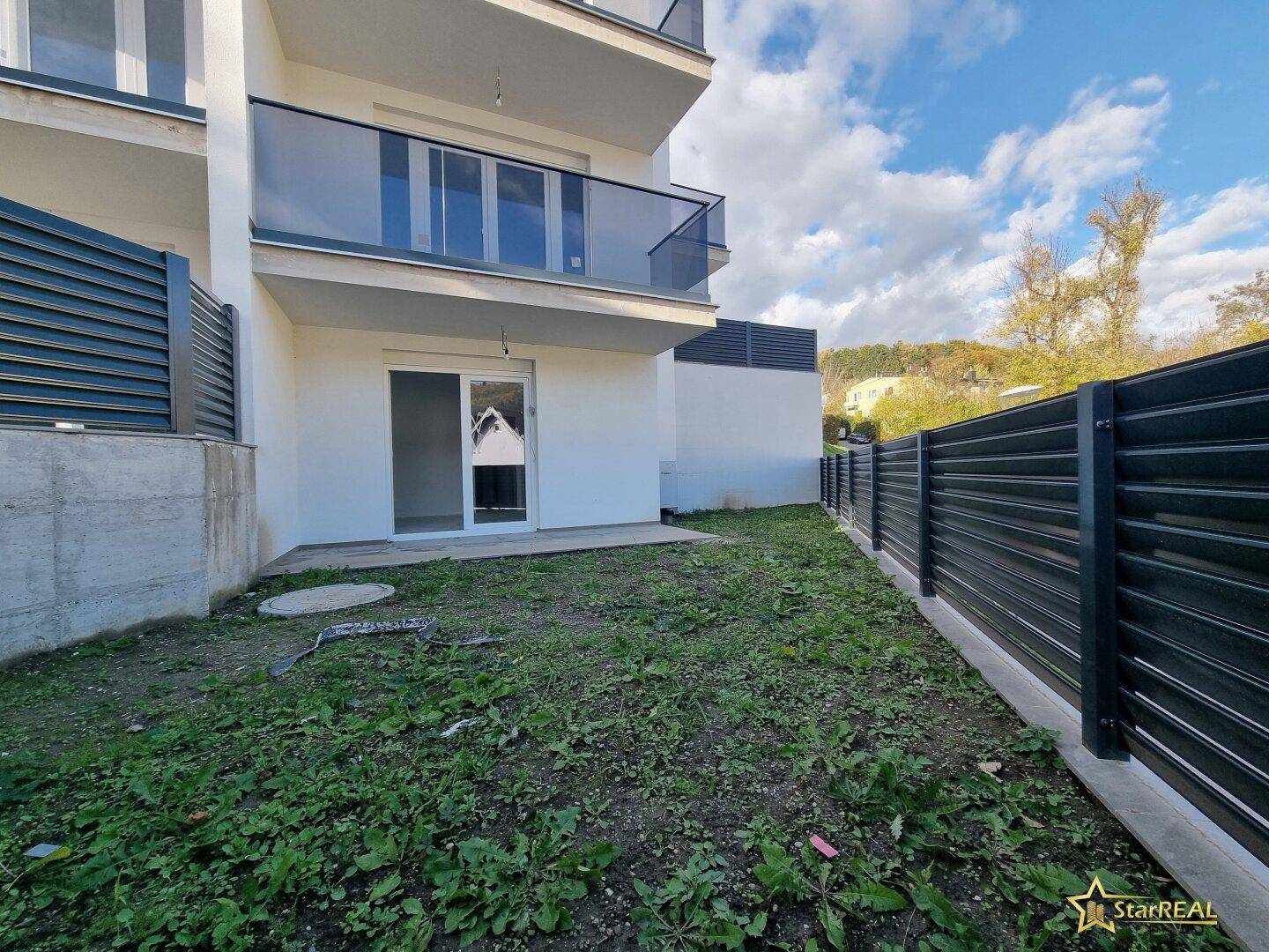 Kleiner Gartenbereich mit Rasenfläche und Zugang zu einer Terrasse am Gebäude.