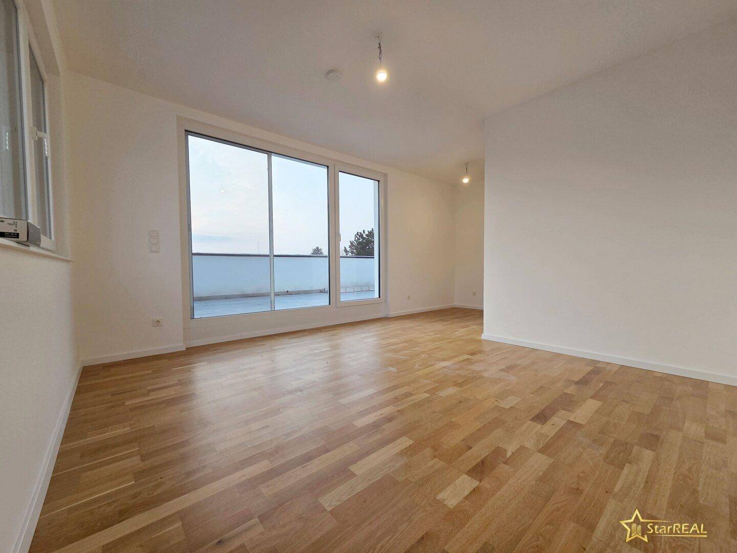 Lichtdurchfluteter Wohnbereich mit Parkettboden und großen Fenstern zur Dachterrasse.