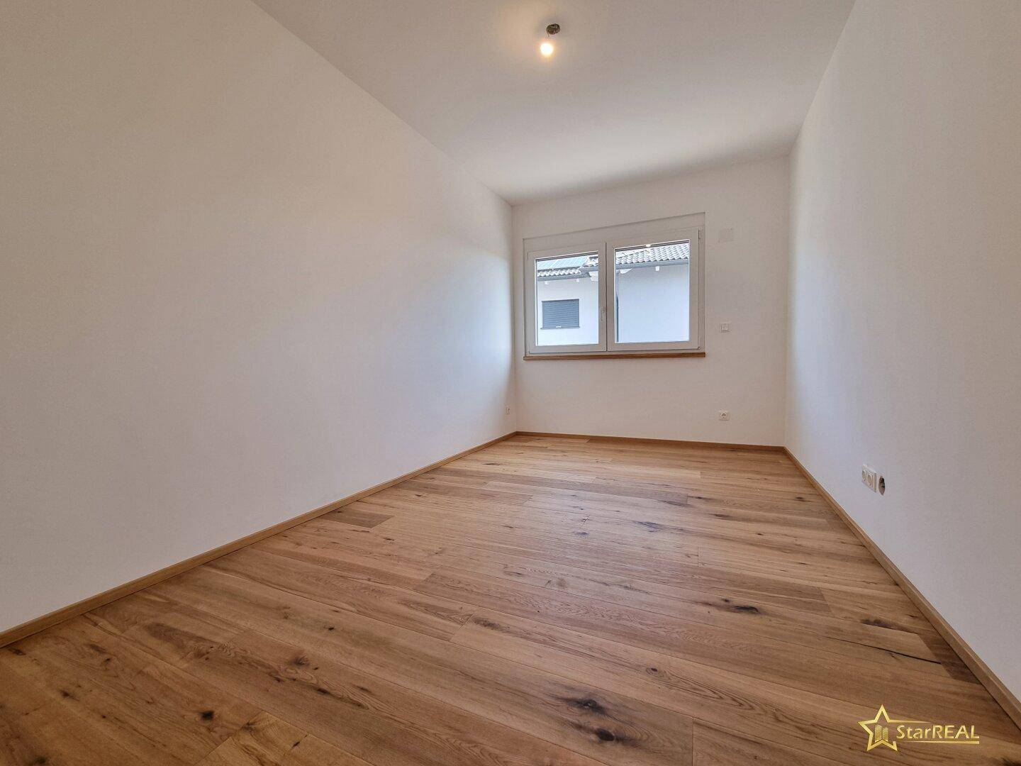 Gemütliches Schlafzimmer mit Eichenparkettboden und einem Fenster, das den Raum erhellt.