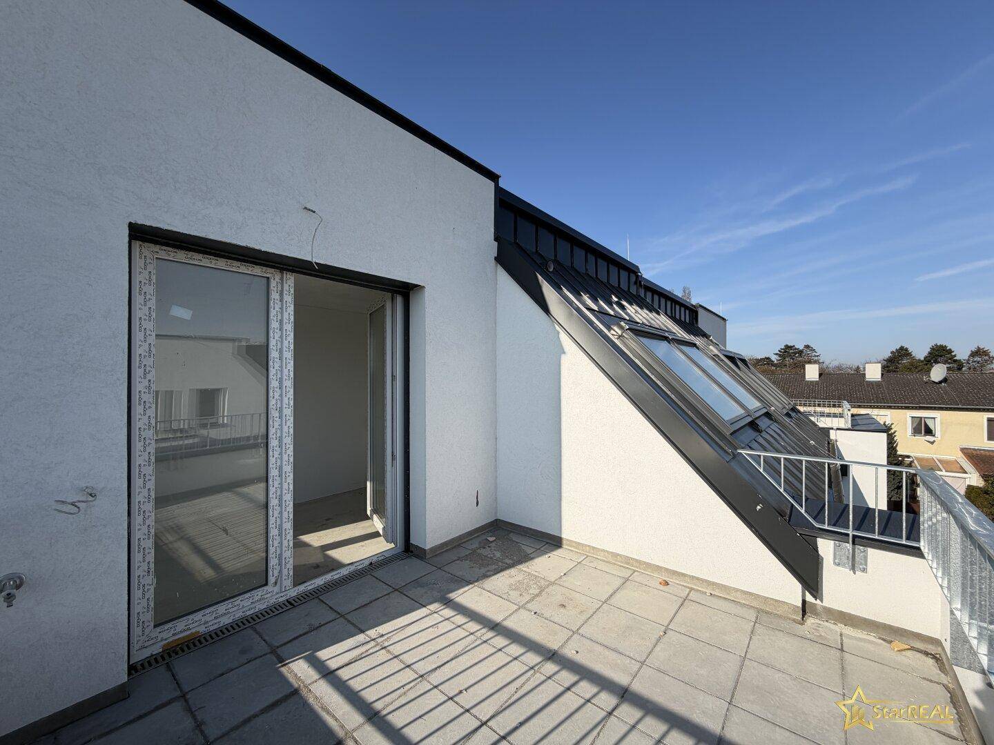 Sonniger Dachterrasse mit Fliesenboden und Blick auf die Umgebung, ideal für Entspannung im Freien.