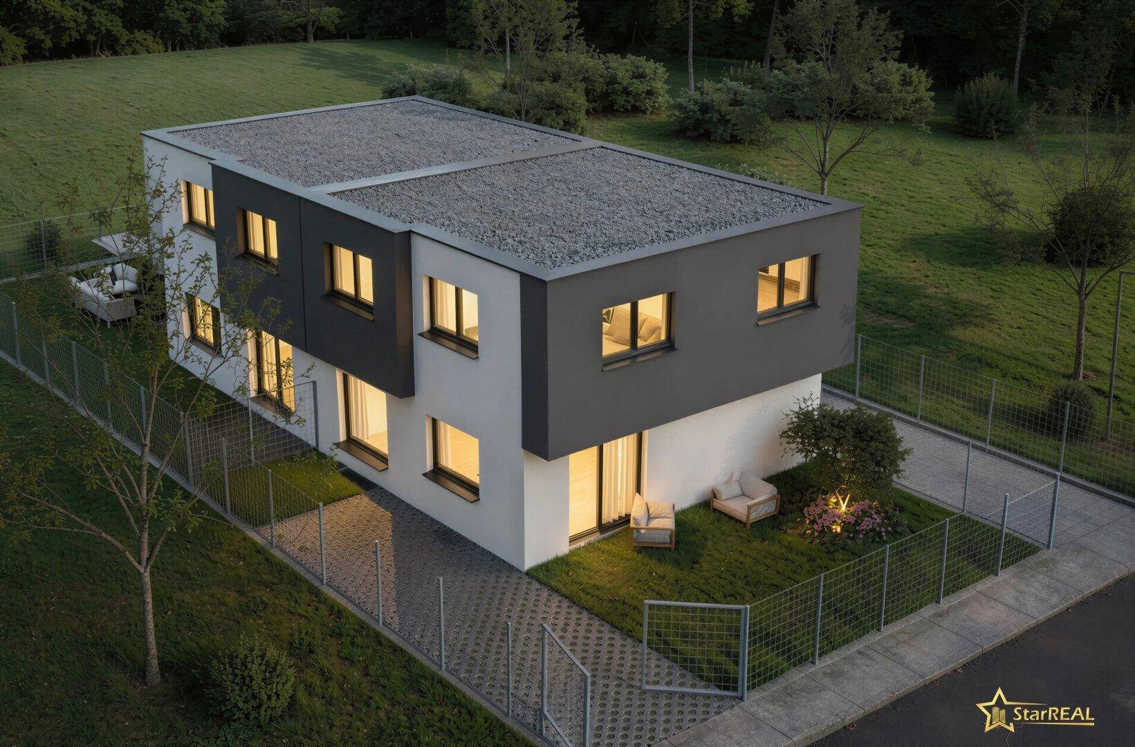 Abendliche Luftaufnahme des modernen Hauses mit beleuchteten Fenstern und Flachdach in grüner Umgebung.