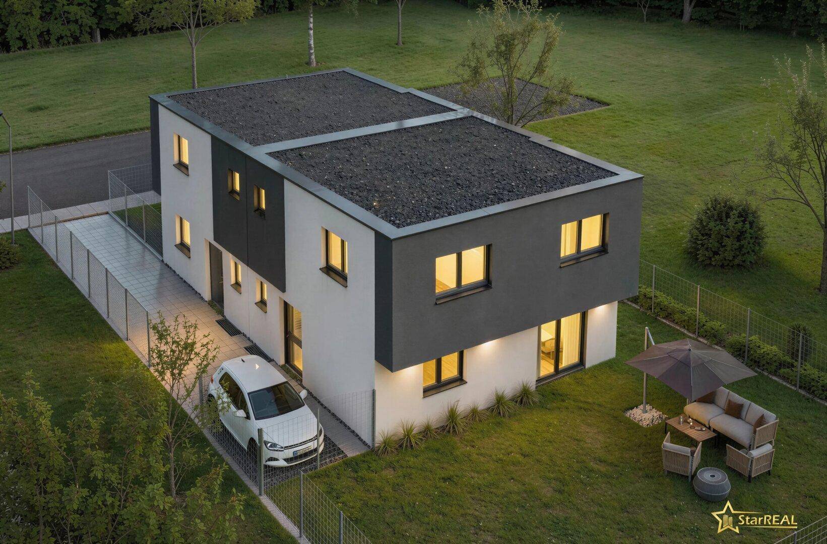 Luftaufnahme des modernen Hauses bei Dämmerung, mit beleuchteten Innenräumen und Flachdach.