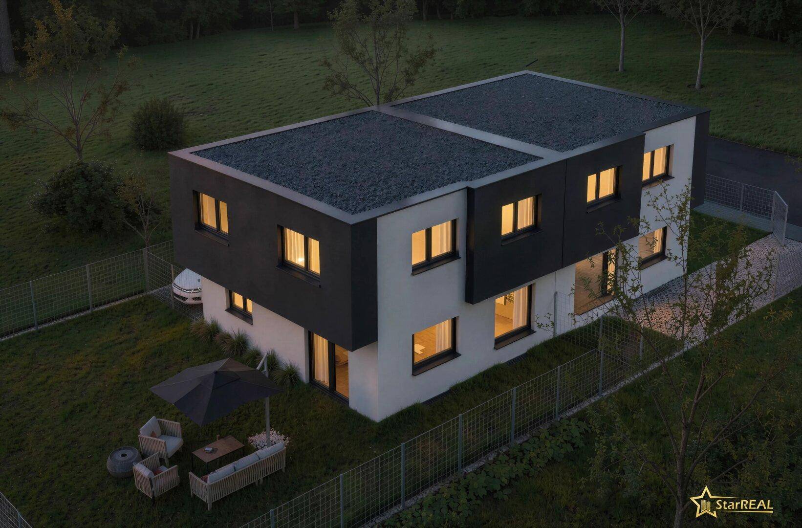 Abendliche Luftaufnahme des modernen Hauses mit beleuchteten Fenstern und Flachdach in grüner Umgebung.