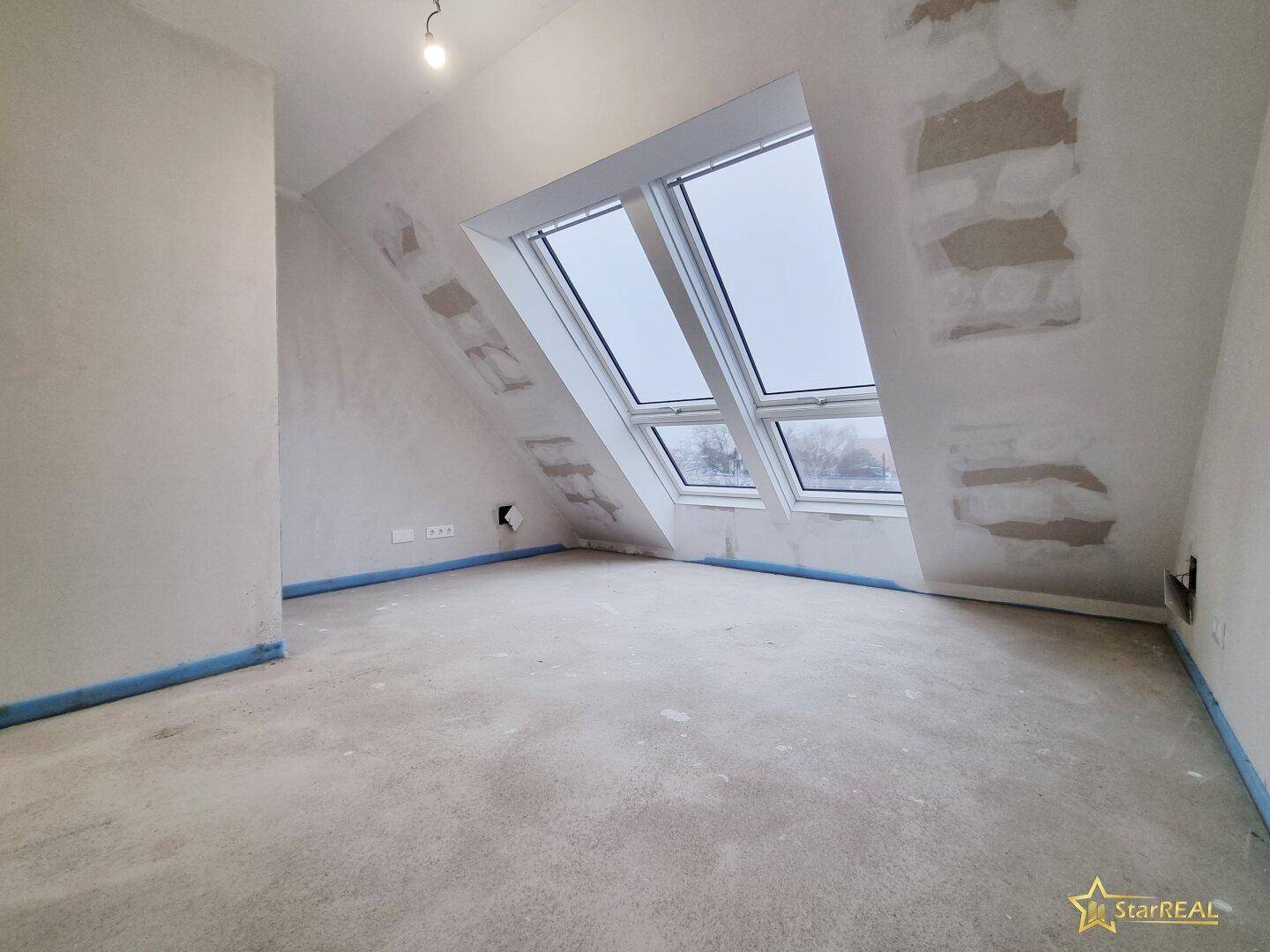 Dachgeschossraum im Ausbauzustand mit großen Dachfenstern für viel Licht.
