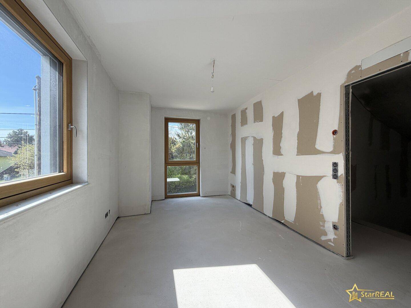 Unfertiger Raum mit Fenster und offenem Durchgang, ideal für individuelle Gestaltung.