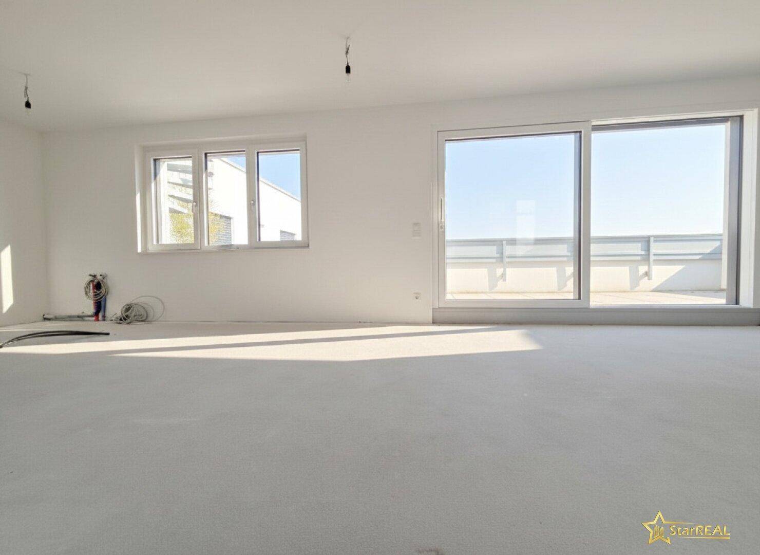 Großer, heller Wohn-Essbereich mit breiter Schiebetür zur Terrasse und Fenstern, die viel Sonnenlicht hereinlassen.