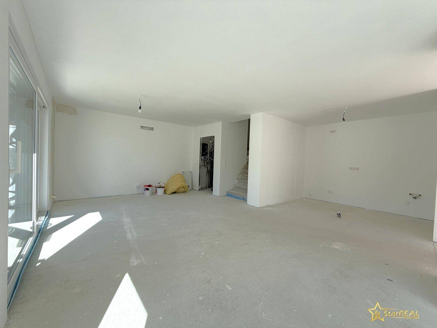 Großer, heller Wohnbereich im Neubau mit Treppenaufgang und viel Potenzial zur Gestaltung.