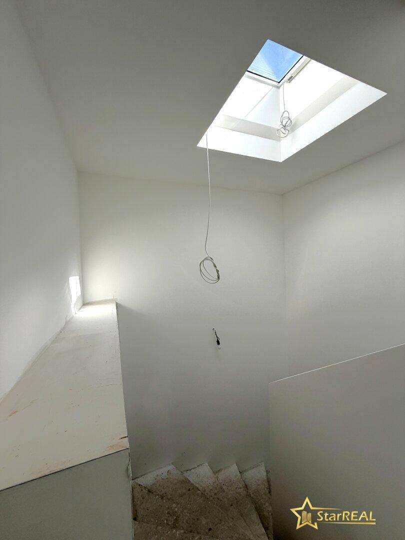 Heller Treppenaufgang im Neubau mit einem Oberlicht, das viel natürliches Licht spendet.