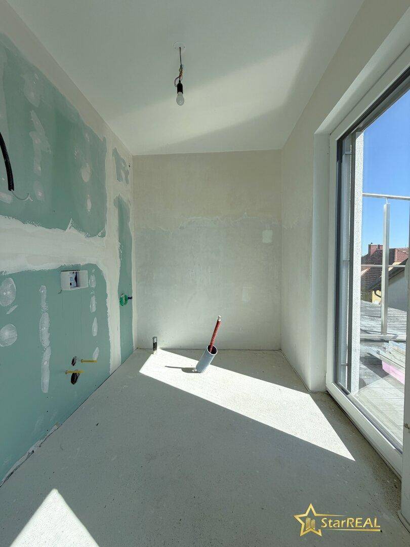 Unfertiges Badezimmer im Neubau mit vorbereiteten Anschlüssen und Zugang zur Dachterrasse.