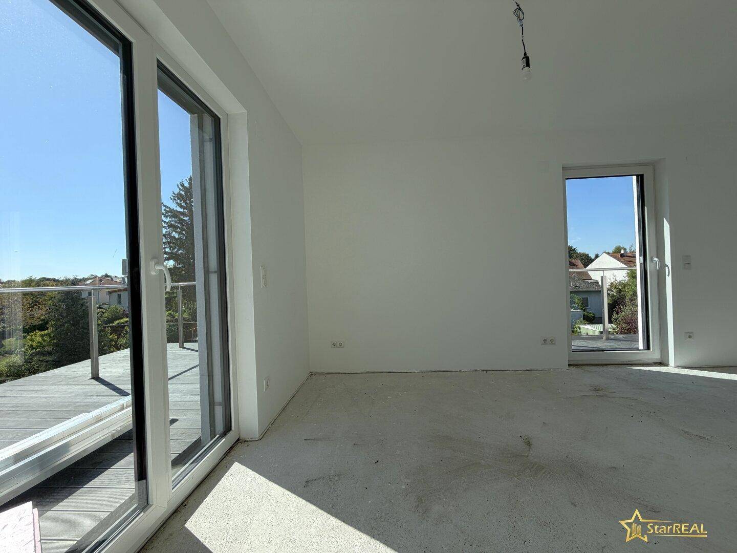 Helles Zimmer im Neubau mit großen Fenstern und direktem Zugang zur weitläufigen Dachterrasse.