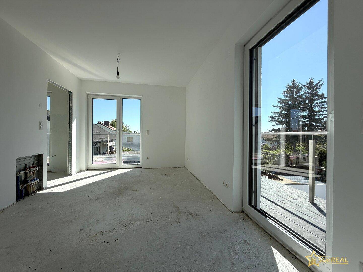 Helles Zimmer im Neubau mit großen Fenstern und direktem Zugang zur weitläufigen Dachterrasse.