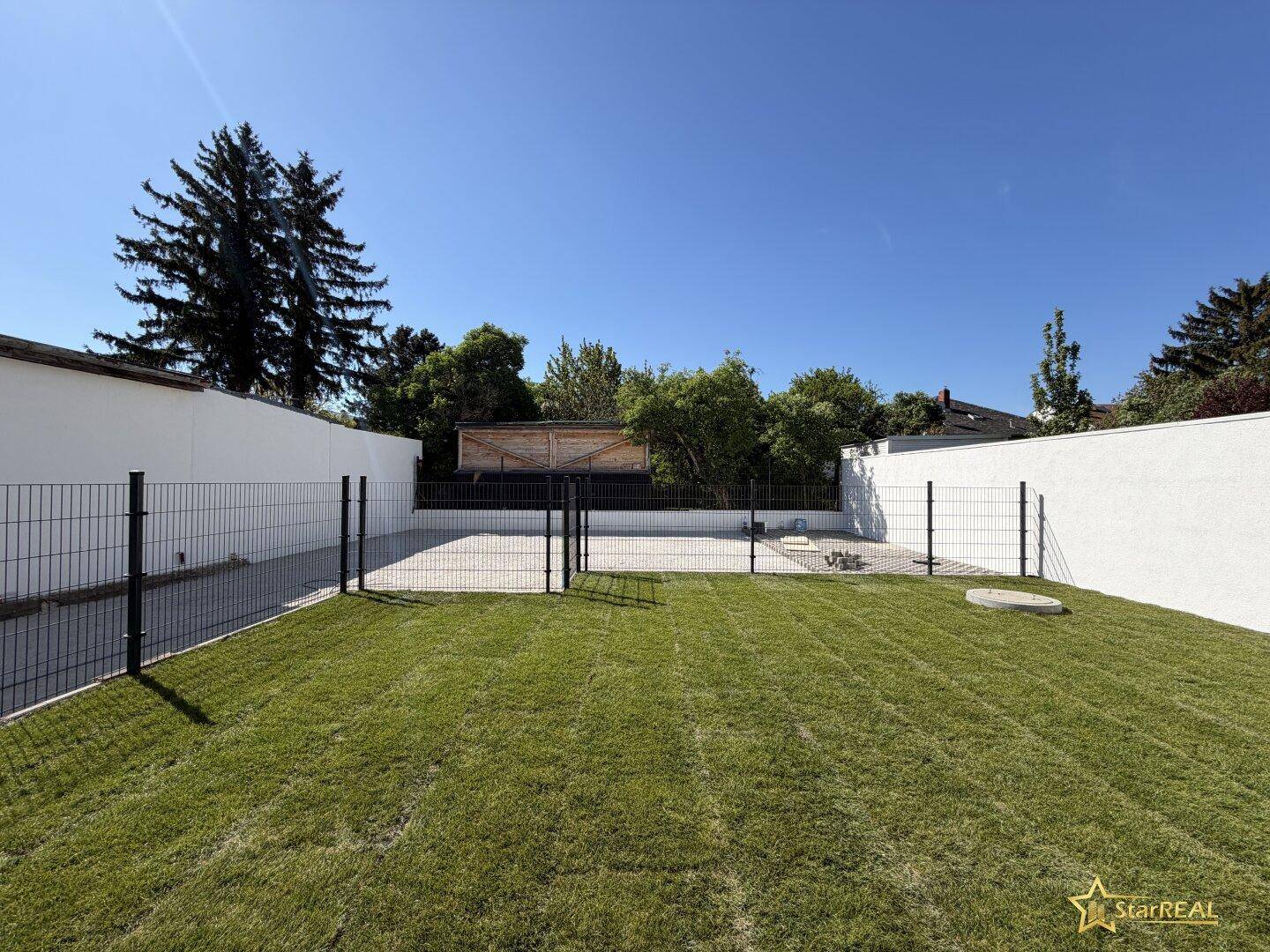 Frisch angelegter Gartenbereich mit Rasen und Zaun, bereit für die individuelle Gestaltung.