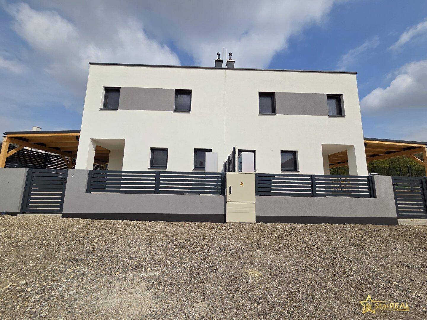 Frontansicht eines modernen Doppelhauses mit weißer Fassade und grauen Akzenten.