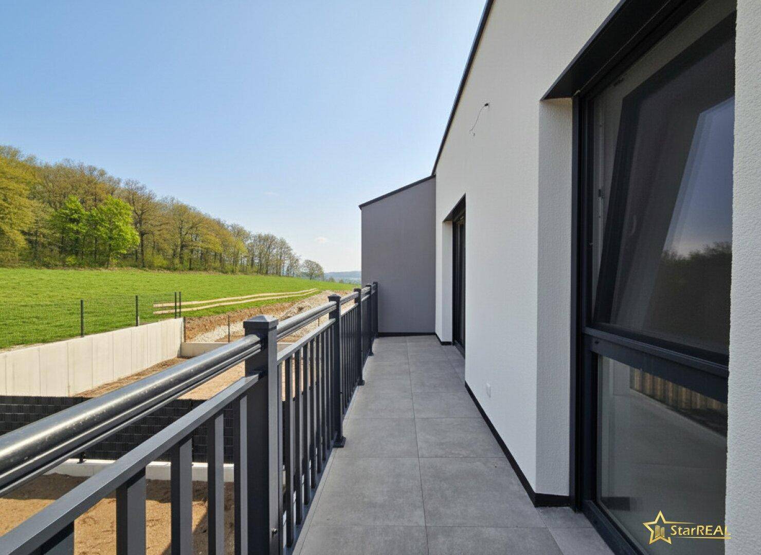 Geräumiger Balkon mit Fliesenboden und weitem Blick ins Grüne.