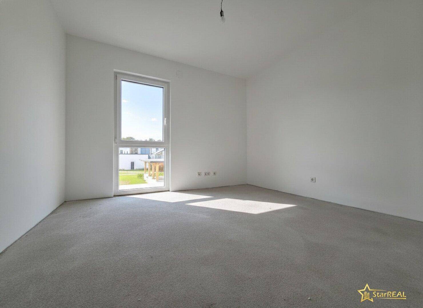 Heller Raum im Rohbau mit weiß gestrichenen Wänden und großem Fenster.