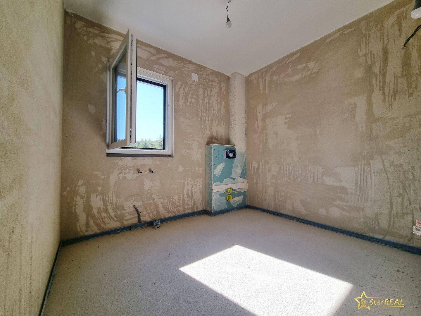 Unfertiger Raum mit rohen Wänden und sichtbaren Installationen für zukünftige Nutzung.