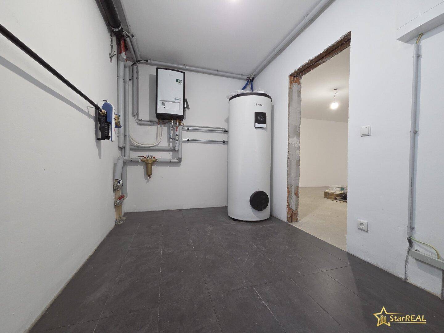 Technikraum im Keller mit Heizungsanlage und Warmwasserspeicher.