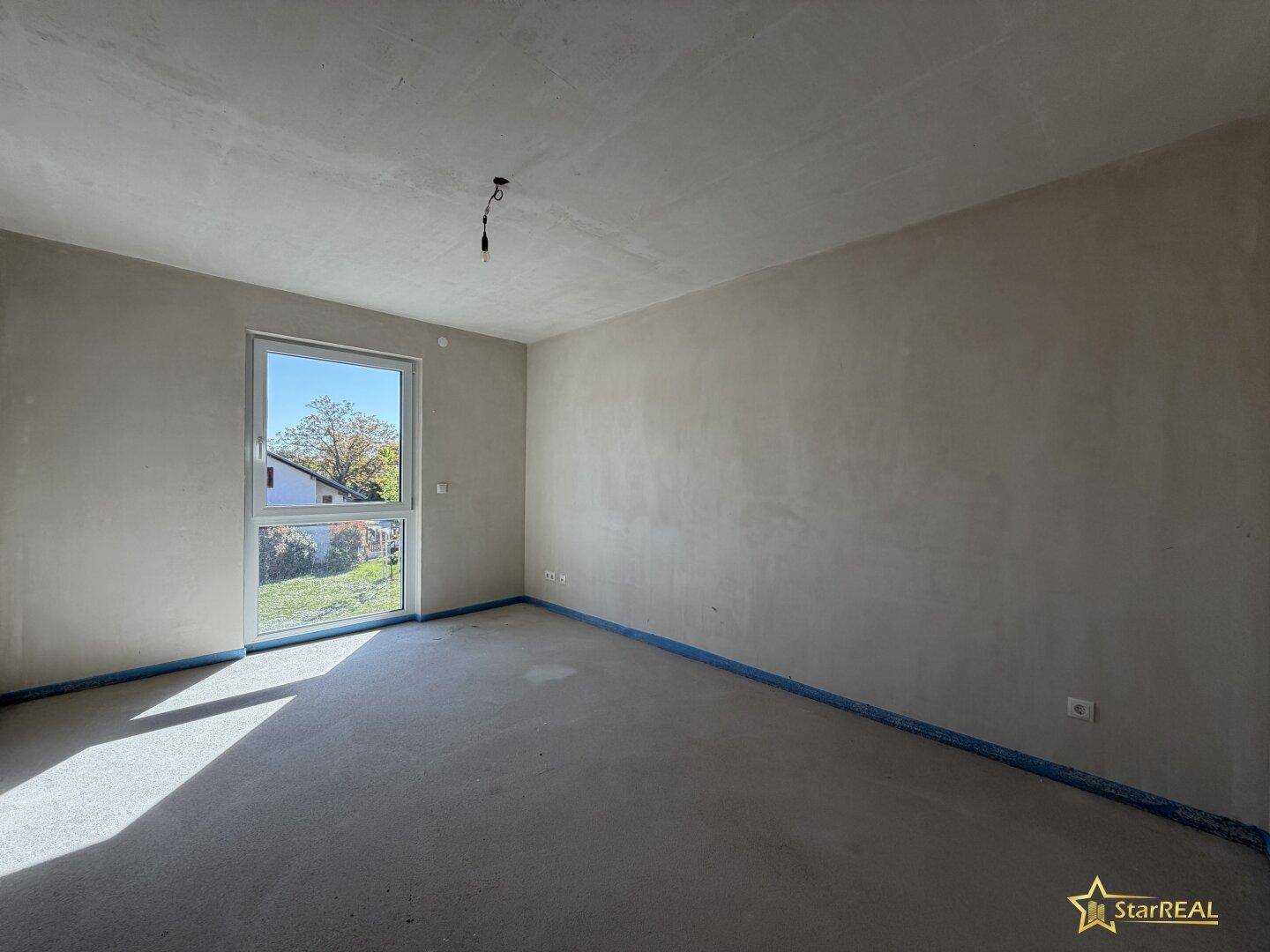 Unfertiges Zimmer mit großem Fenster und viel Tageslicht, bereit für die Gestaltung.