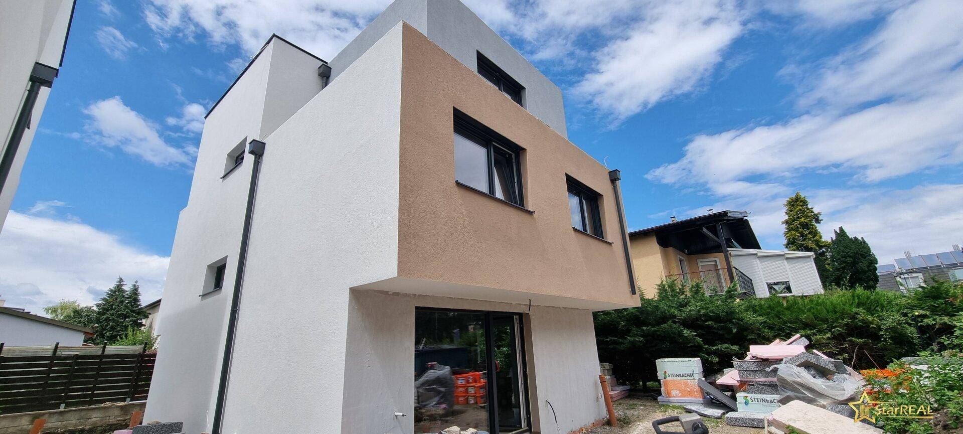 Seitenansicht eines im Bau befindlichen Reihenhauses mit moderner Fassadengestaltung.