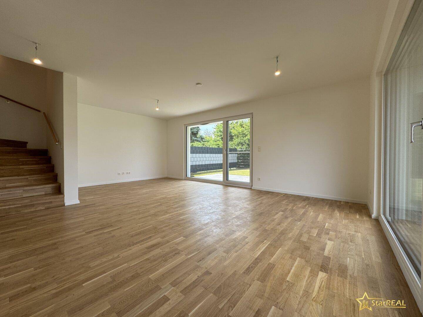 Helles Wohnzimmer mit Eichenparkett und Zugang zur Terrasse durch große Schiebetüren.
