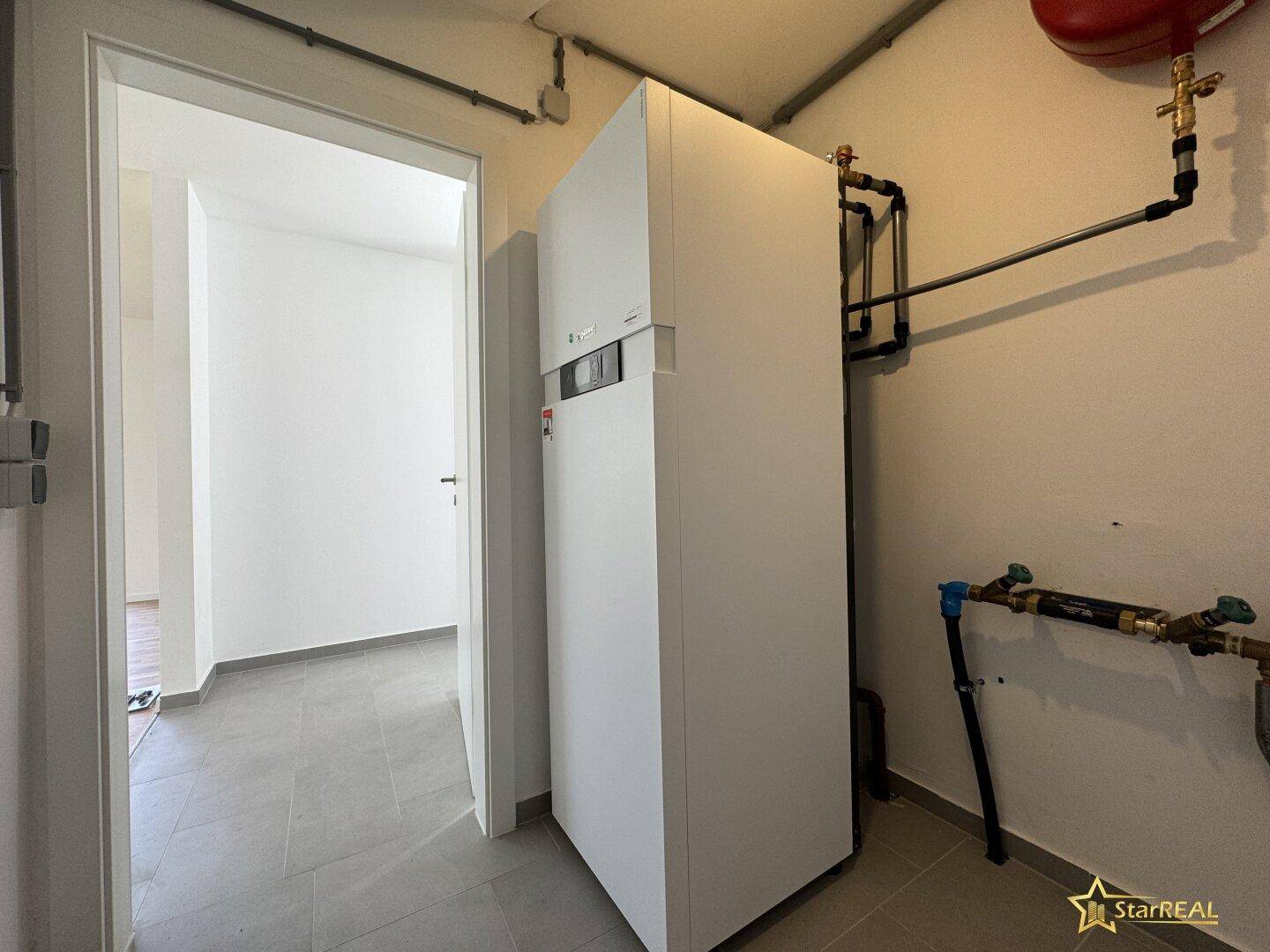 Technikraum mit moderner Wärmepumpe und Fliesenboden.