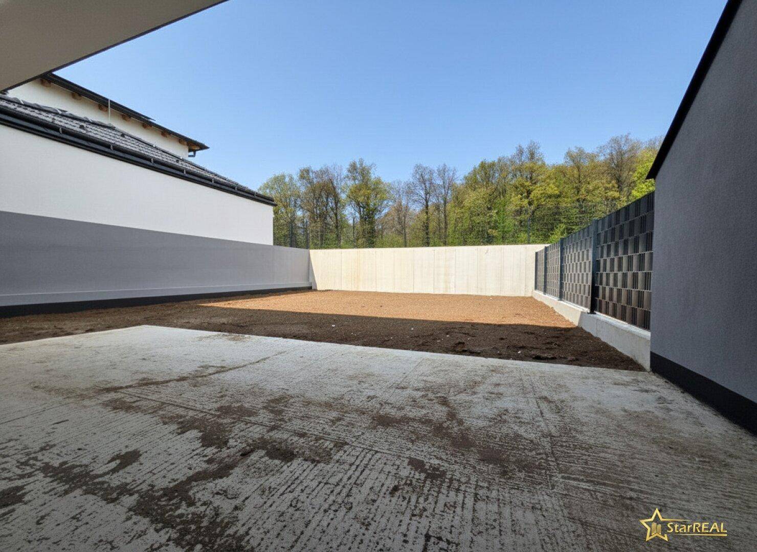 Leerer Hinterhof mit vorbereitetem Boden für die Gartengestaltung.