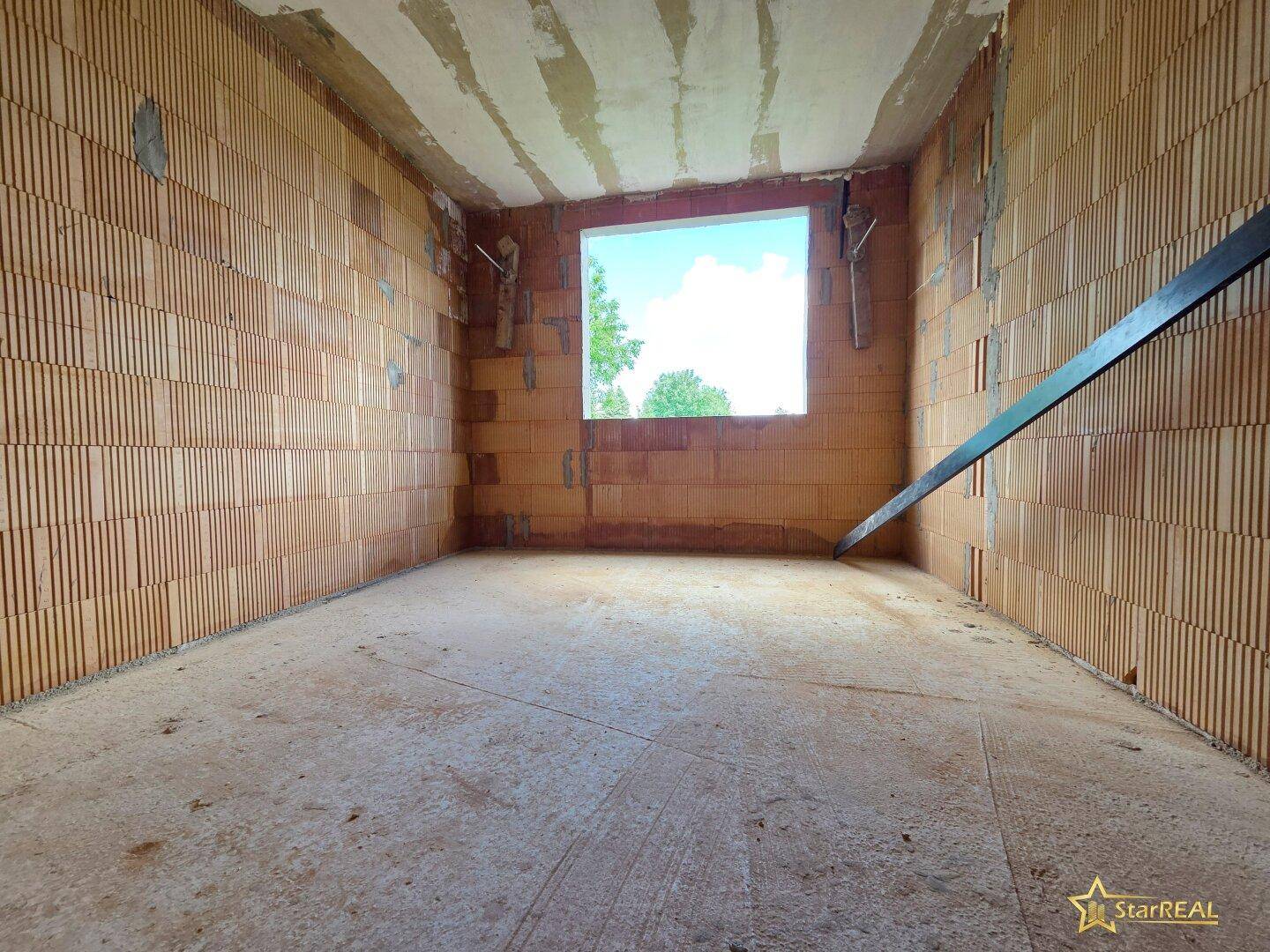 Kleinerer Rohbau-Raum mit Ziegelwänden und einer Fensteröffnung für natürliches Licht.