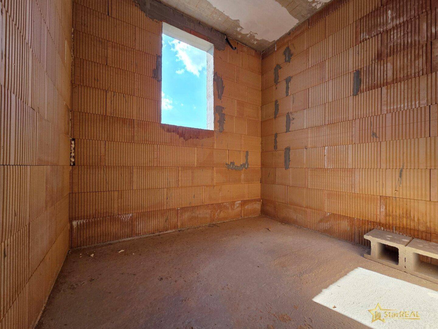 Kleinerer Rohbau-Raum mit Ziegelwänden und einer Fensteröffnung.