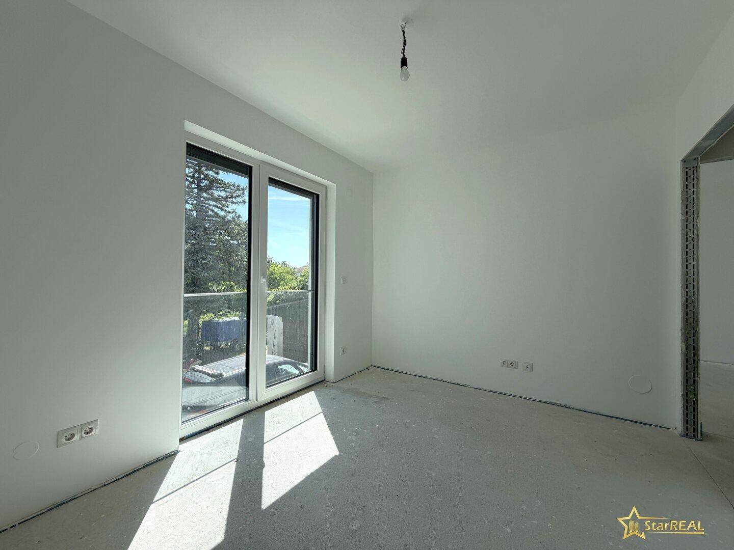 Heller Raum im Neubau mit Balkonzugang und viel Sonnenlicht, ideal als Schlafzimmer.